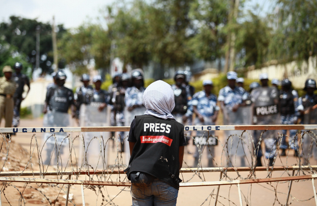 A lone female journalist with The Independent Magazine Uganda stands right in front of a sea of Policemen Source Echwalu Photography